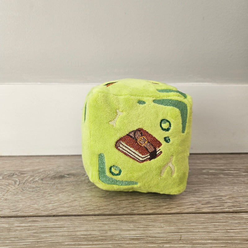 Green plush toy with a brown center attached to a wooden surface