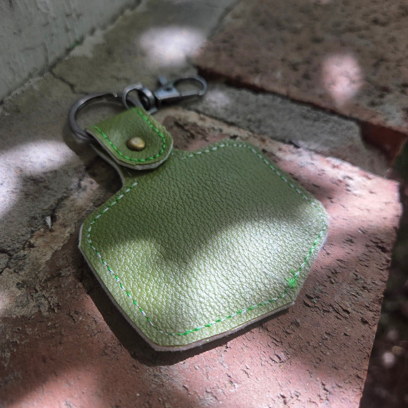 Green leather keychain on a textured surface