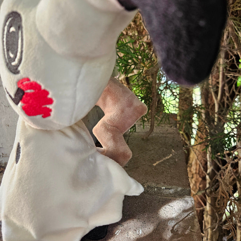 Close-up of a plush toy with a red heart and black and white design, surrounded by natural elements.