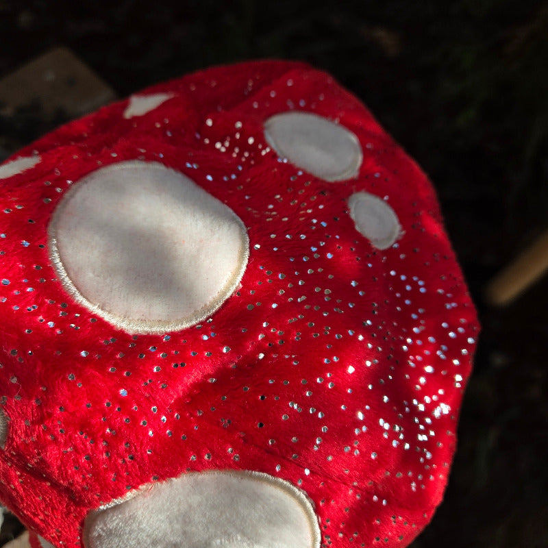Red mushroom-shaped object with white spots on a dark background