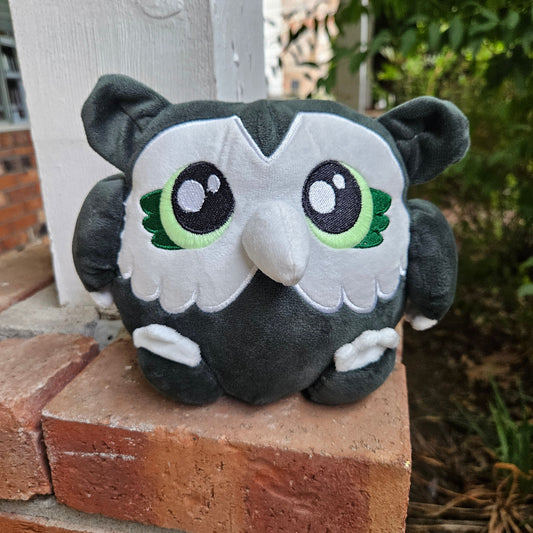 Plush toy resembling a panda with green accents on a brick wall.