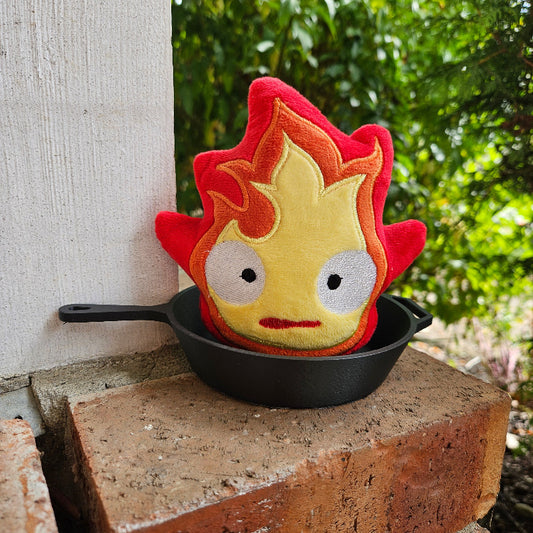 Flame-shaped pot holder on a black cast iron skillet against a natural background