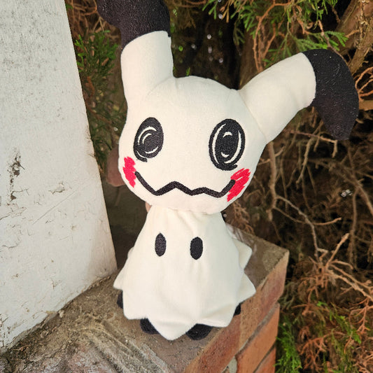 Plush toy resembling a ghost character with black accents on a stone surface.