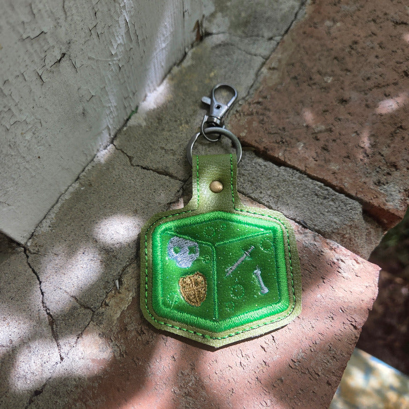 Green keychain with a geometric design on a stone surface