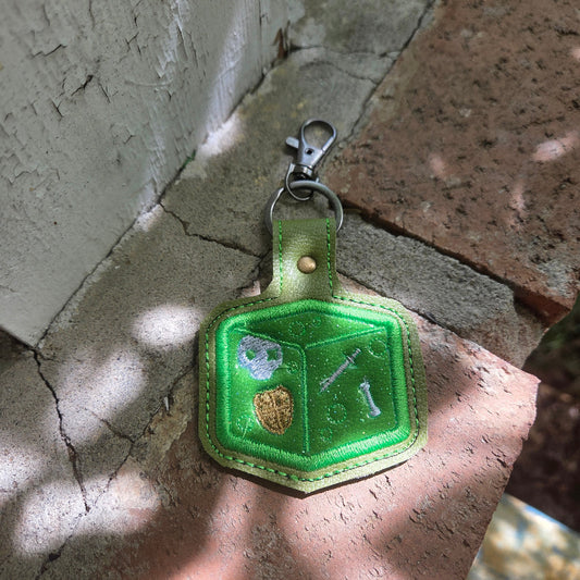 Green keychain with a geometric design on a stone surface