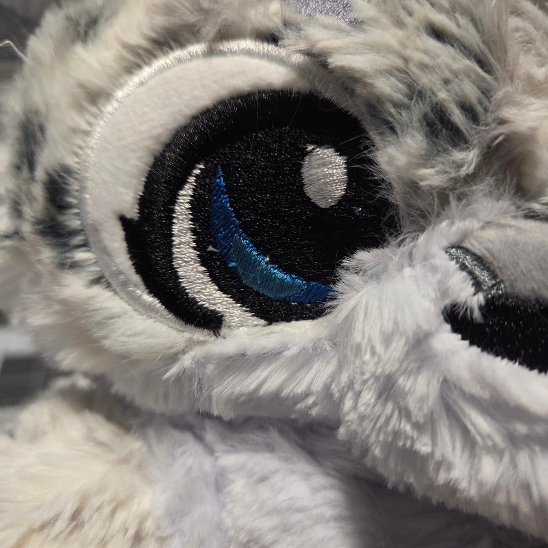 Close-up of a plush toy with a patch featuring a blue and white design.