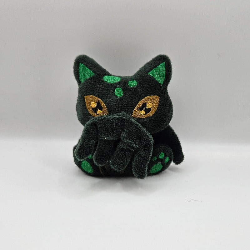 Black cat-shaped toy with green spots on a white background