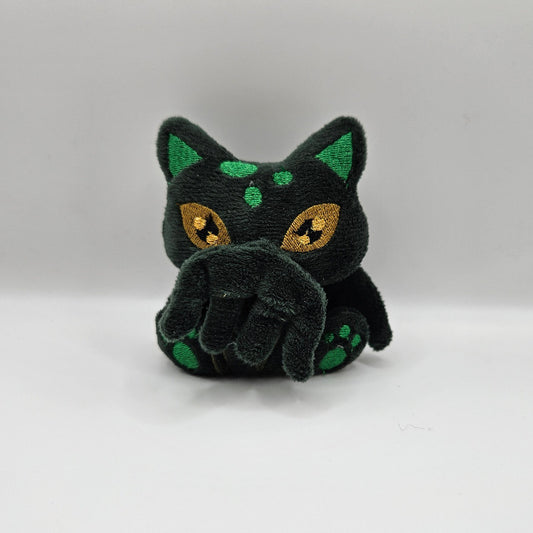 Black cat-shaped toy with green spots on a white background