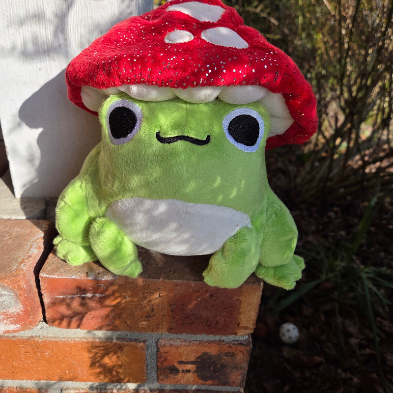 Plush toy resembling a green character with a red shell on a brick surface