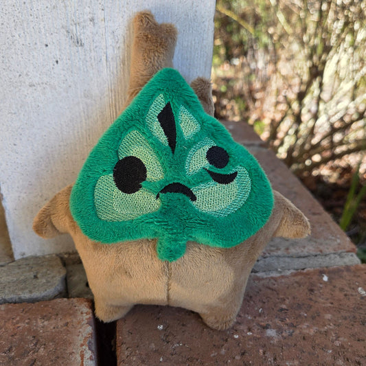 Plush toy with a green face on a stone surface