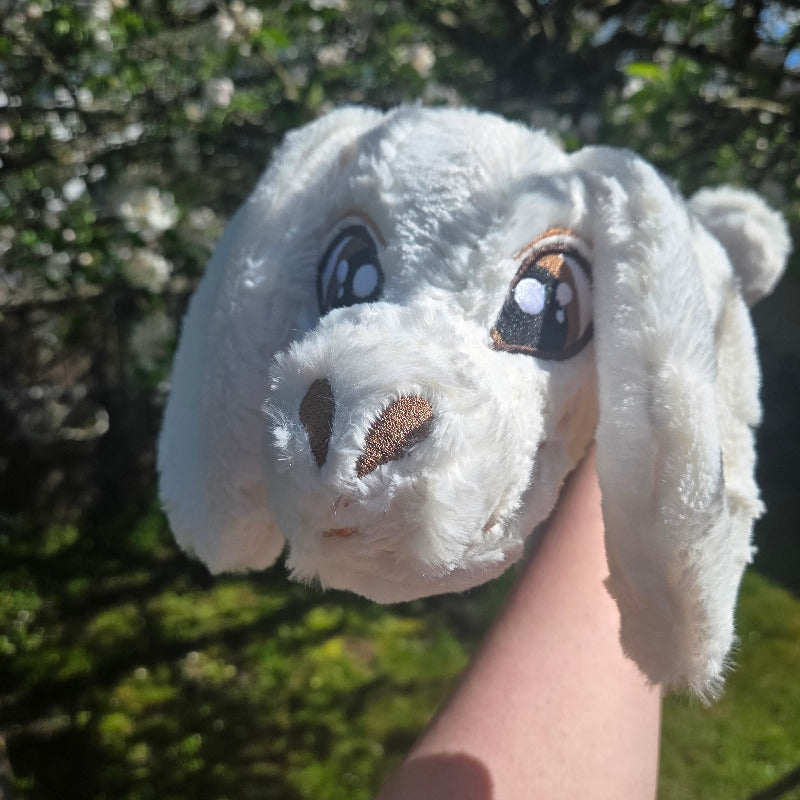 Close-up of a plush toy resembling a white creature with a blurred natural background