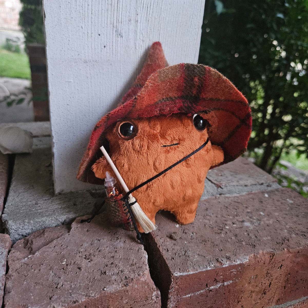 Plush toy resembling a frog with a backpack on a stone wall