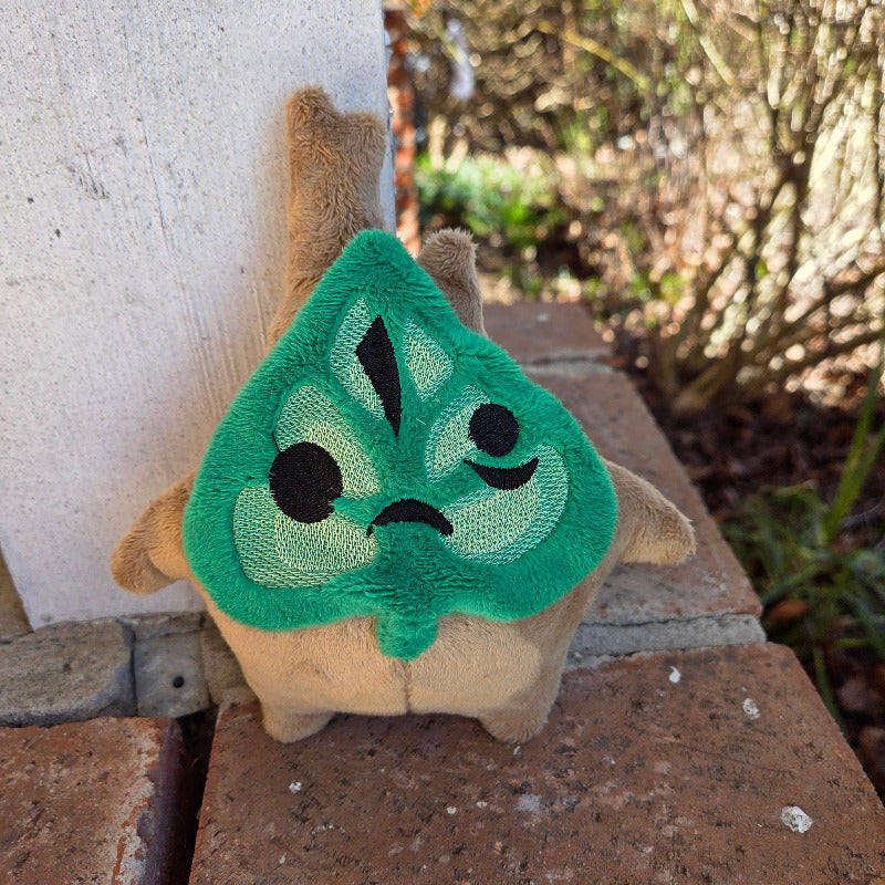 Plush toy with green face and black eyes on a stone surface
