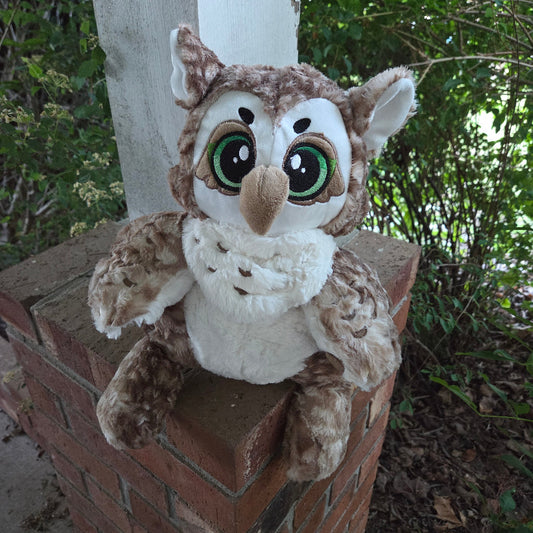 Plush owl toy on a wooden surface with a natural background